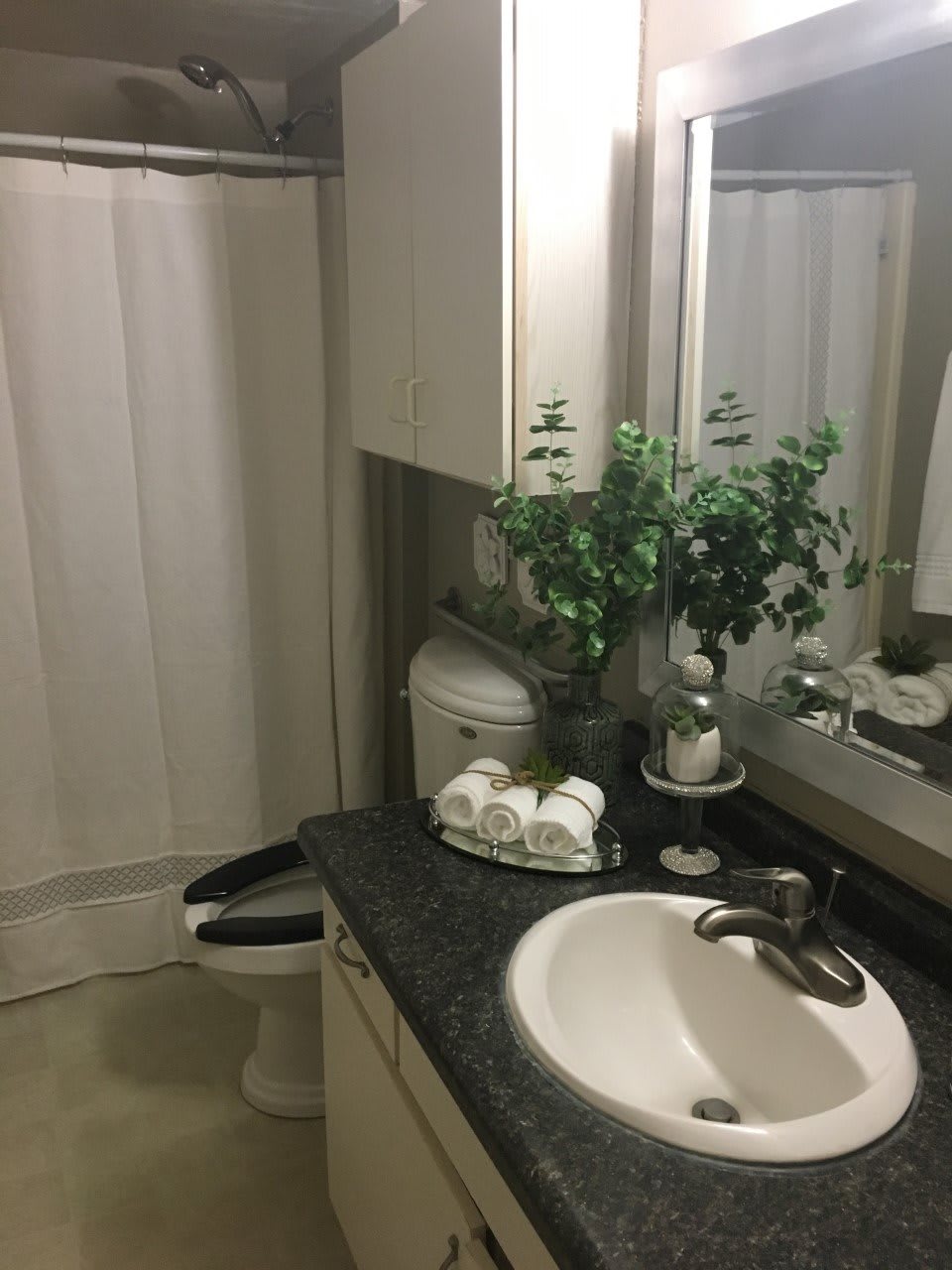 A clean and organized bathroom with a sink, mirror, and shower curtain.
