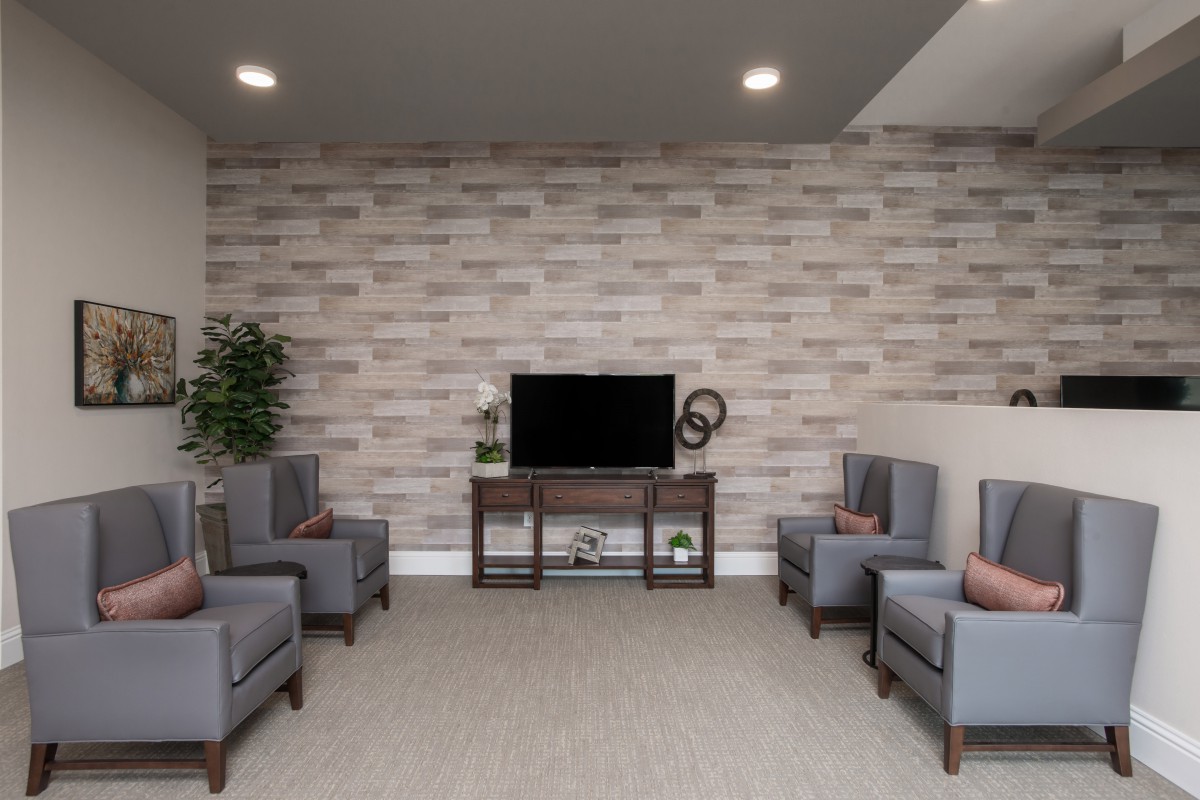 A modern living room with stylish seating and a TV against a brick accent wall.