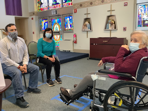 A group of individuals engaged in a conversation in a community space, with one person seated in a wheelchair.