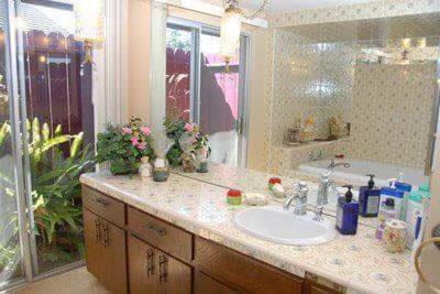 A well-decorated bathroom featuring a large mirror, plants, and a tidy countertop with a sink.