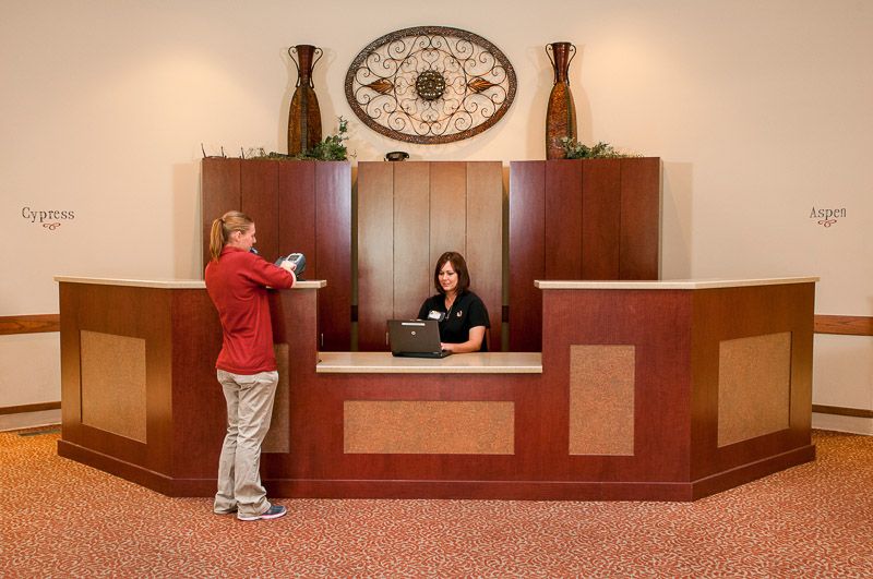 A receptionist assists a visitor at an office front desk.