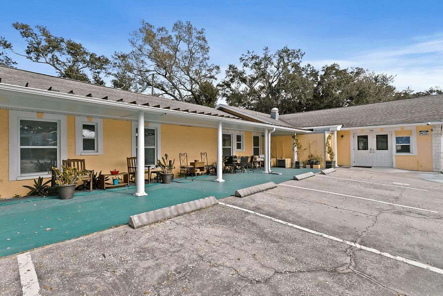 A small yellow motel with a parking lot and surrounding trees.