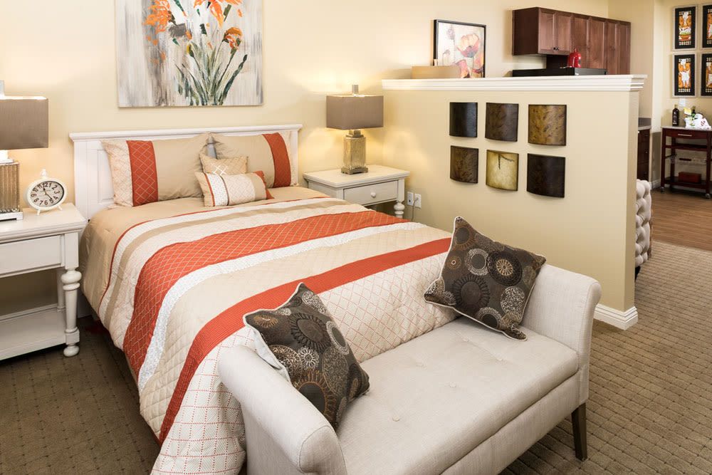 A cozy bedroom with a striped bedspread, decorative pillows, and modern artwork.