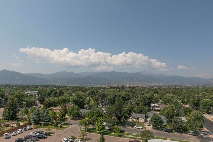 A scenic view of a neighborhood with mountains and clouds in the background.