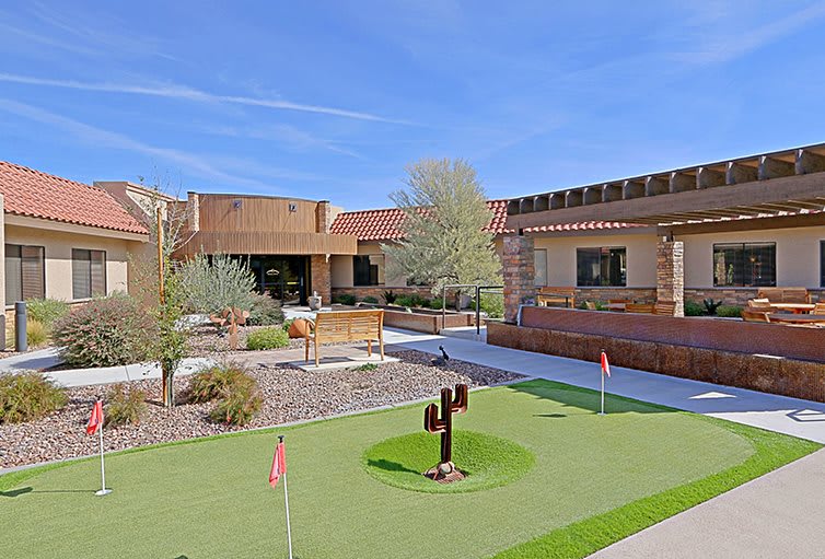 An exterior view of a building with a mini golf course in the courtyard on a clear day.
