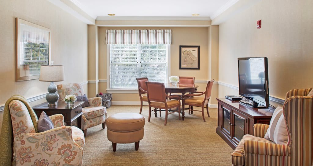 A cozy living room with a central dining table, comfortable seating, and a television.