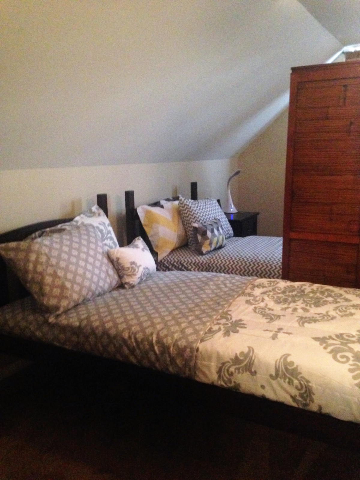 A cozy attic bedroom with twin beds and decorative pillows.