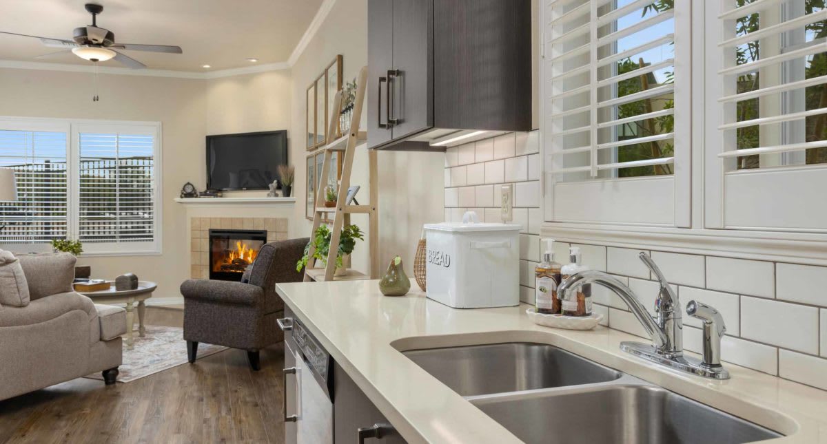 A modern open-plan kitchen and living room with a sleek countertop, sink, and cozy fireplace.