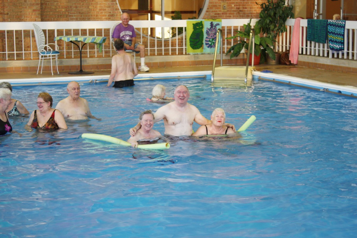 A group of people enjoying their time in a swimming pool with float noodles.