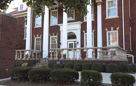 A historic brick building with large columns and an ornate entrance.