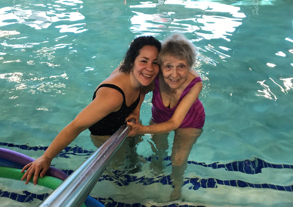 An elderly woman and a younger woman enjoying time together in a swimming pool.