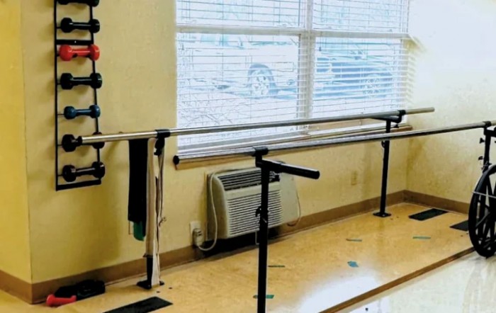 A physical therapy room with parallel bars for rehabilitation exercises.