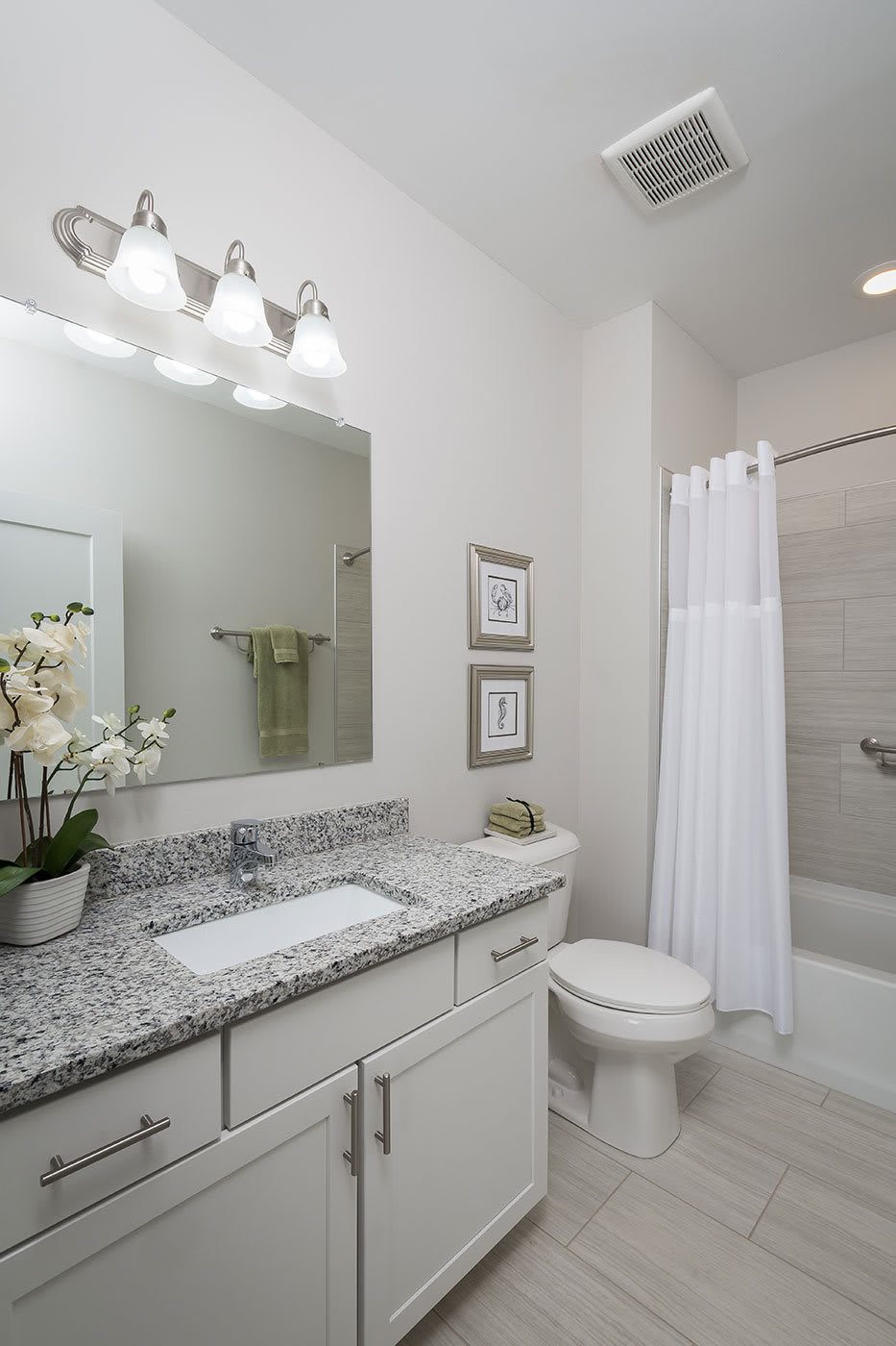 A modern bathroom with a granite countertop, large mirror, and minimalist decor.