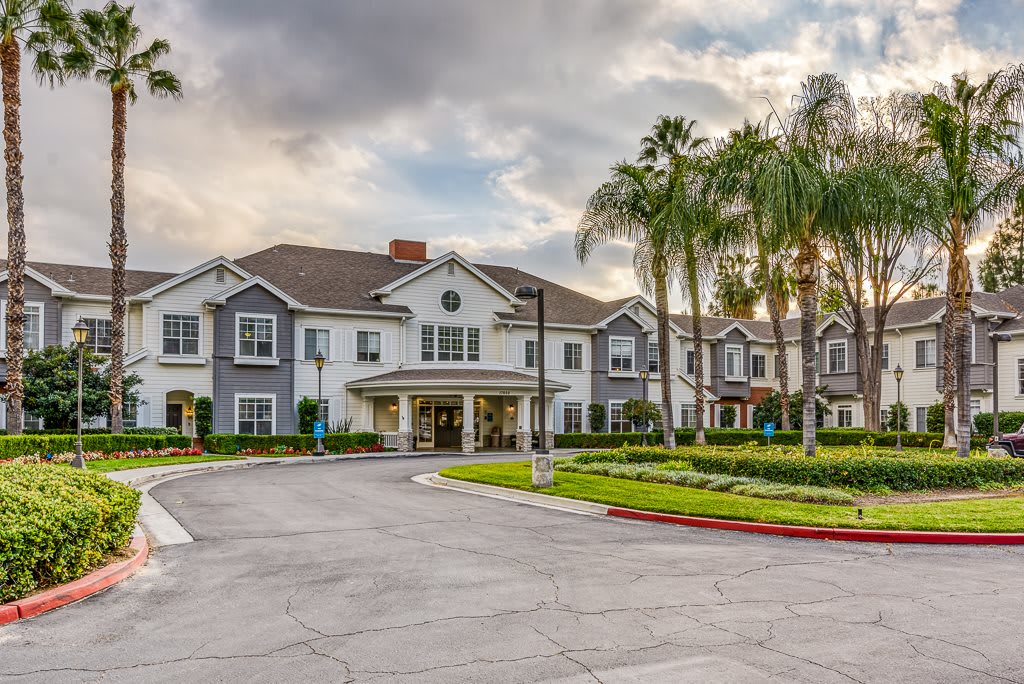 A residential building with palm trees and a driveway under a cloudy sky.