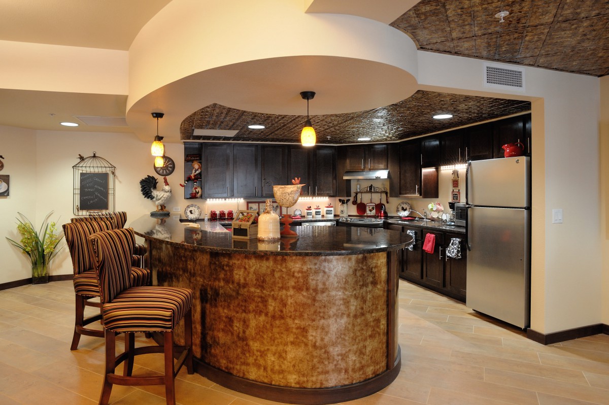 A modern kitchen featuring a stylish bar counter with pendant lighting, stainless steel appliances, and a cozy seating area.