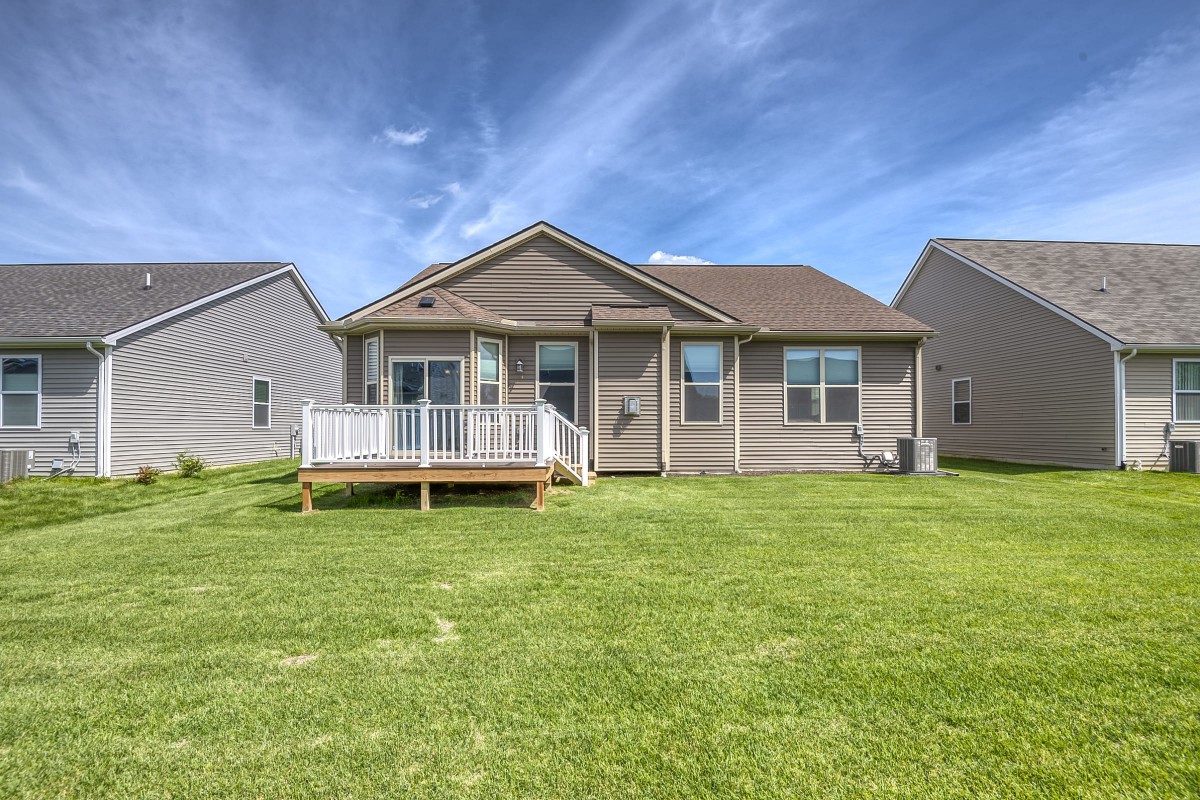 A suburban house with a spacious backyard and a wooden deck.