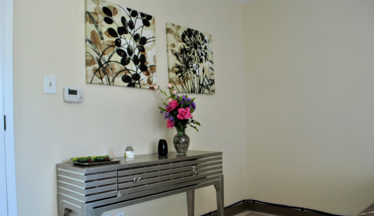 A chic interior space featuring a metallic console table adorned with a floral arrangement in a vase, complemented by abstract artwork on the wall.