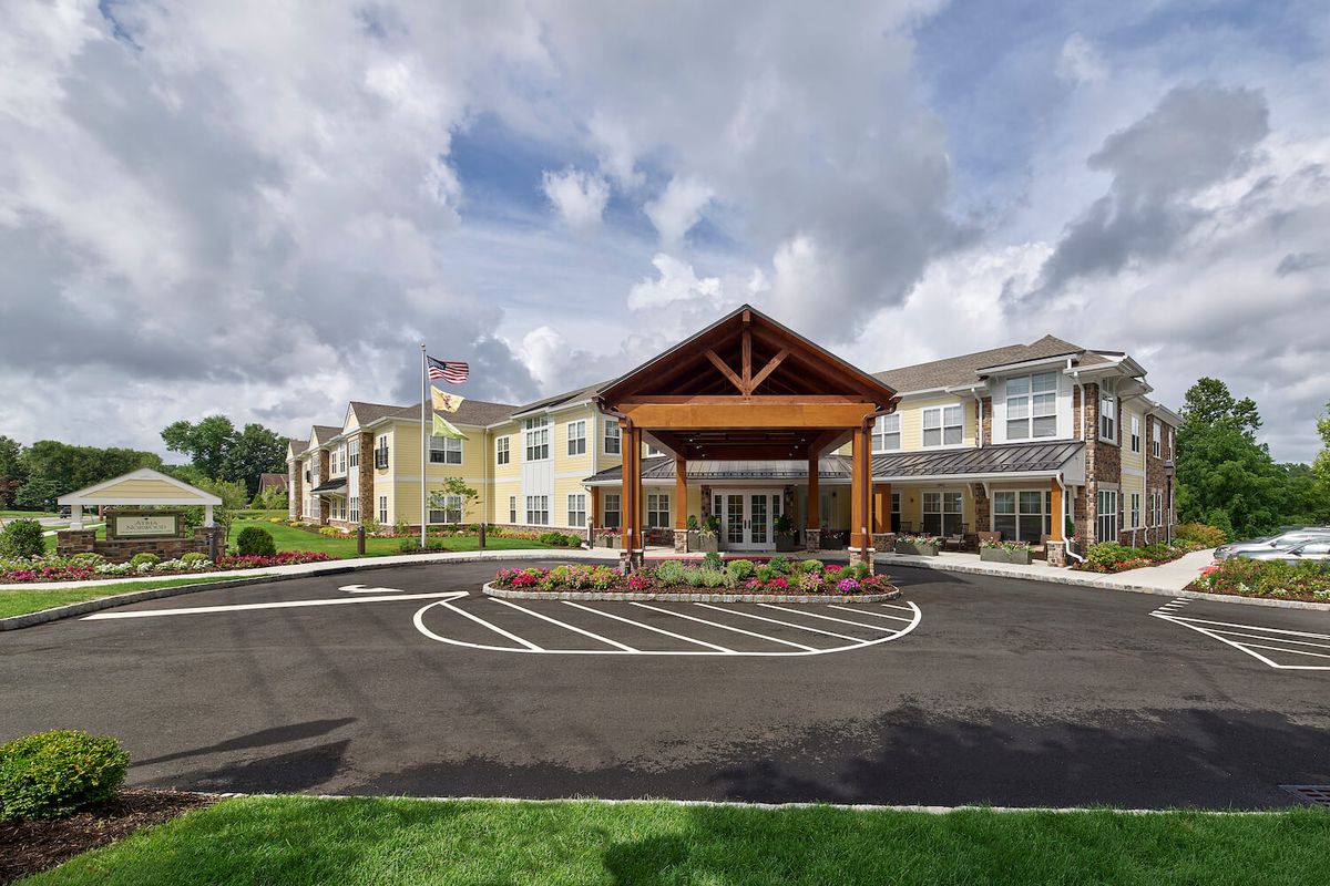 A modern building with a welcoming entrance and landscaped surroundings under a cloudy sky.