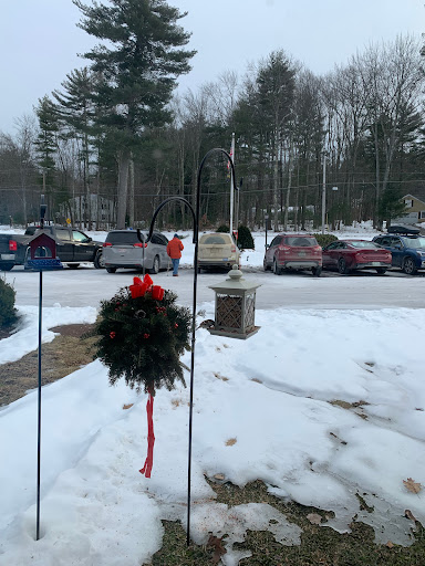 A snowy winter scene featuring a holiday wreath and parked cars.