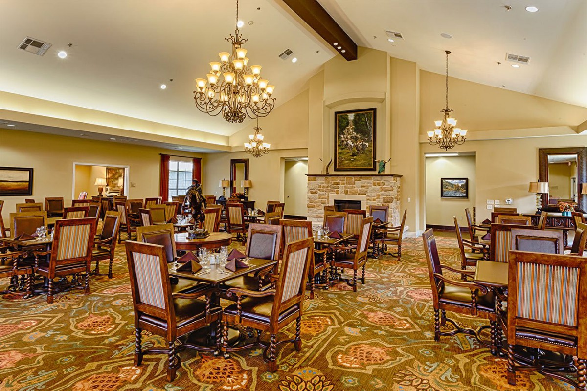 An elegant dining area with chandeliers, neatly arranged tables and chairs, featuring a warm and inviting atmosphere.