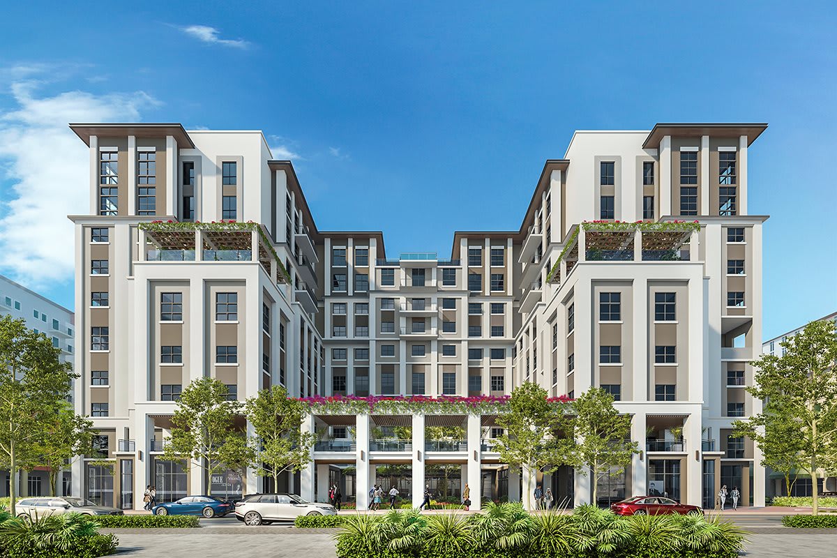 A modern multi-story building with a symmetrical facade and greenery, set against a clear blue sky.