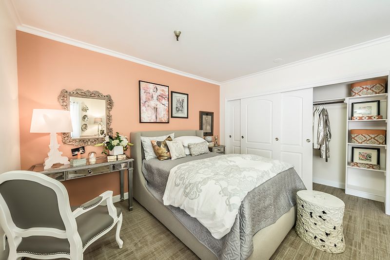 A cozy bedroom with a soft color palette featuring a bed, vanity, and closet space.