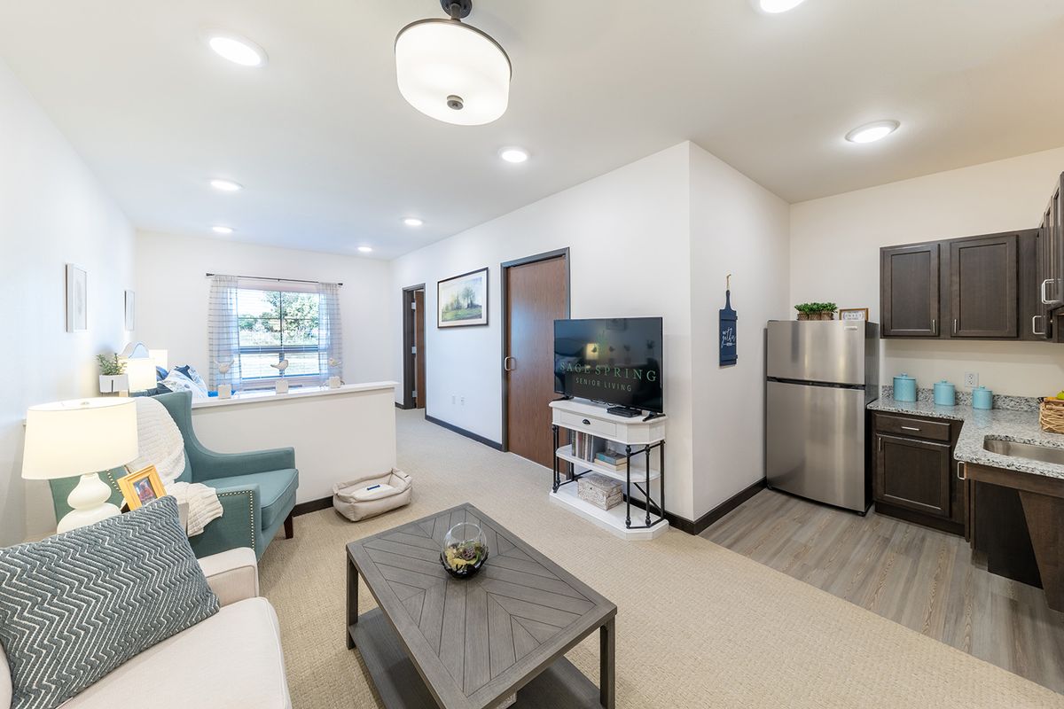 A modern, open-plan living room and kitchen area with bright lighting and contemporary furnishings.