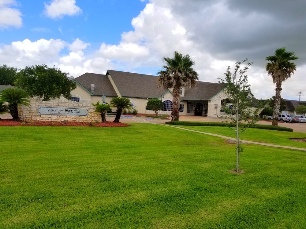 A scenic view of a building surrounded by a well-maintained lawn and palm trees under a cloudy sky.
