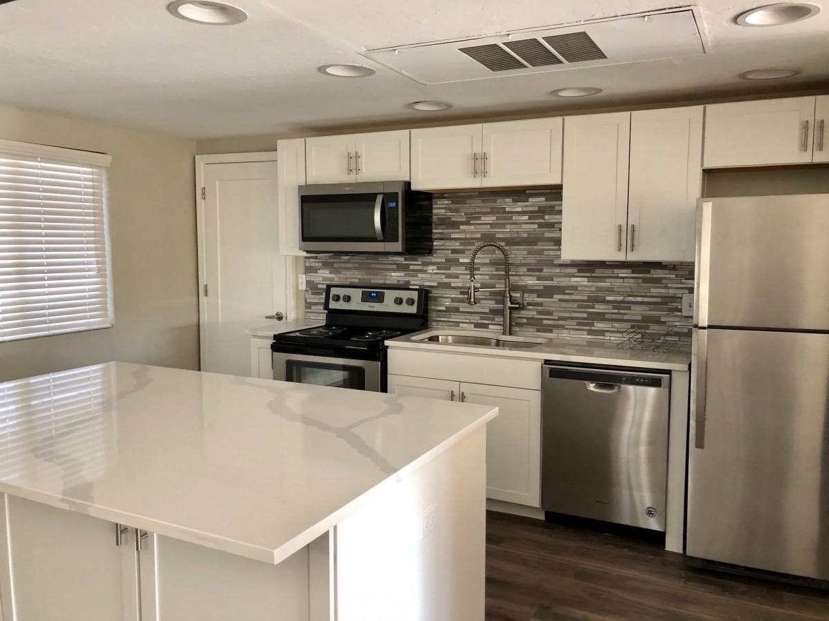 A modern kitchen with white cabinets, stainless steel appliances, and a kitchen island.