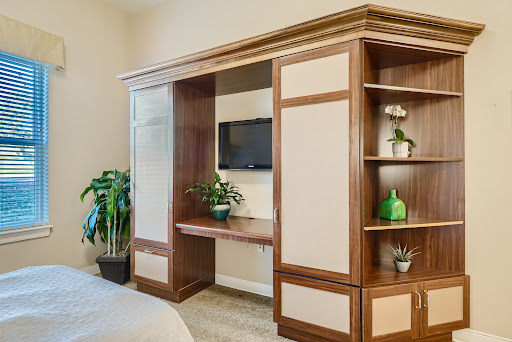 A cozy living space featuring modern wooden furniture with a mounted TV and decorative plants.