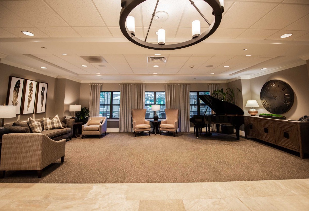A spacious and elegantly decorated lounge with comfortable seating and a grand piano.