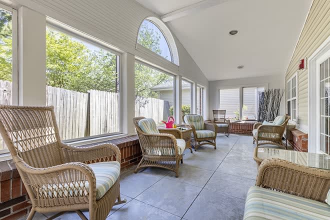 A bright sunroom with wicker furniture and large windows allowing natural light.