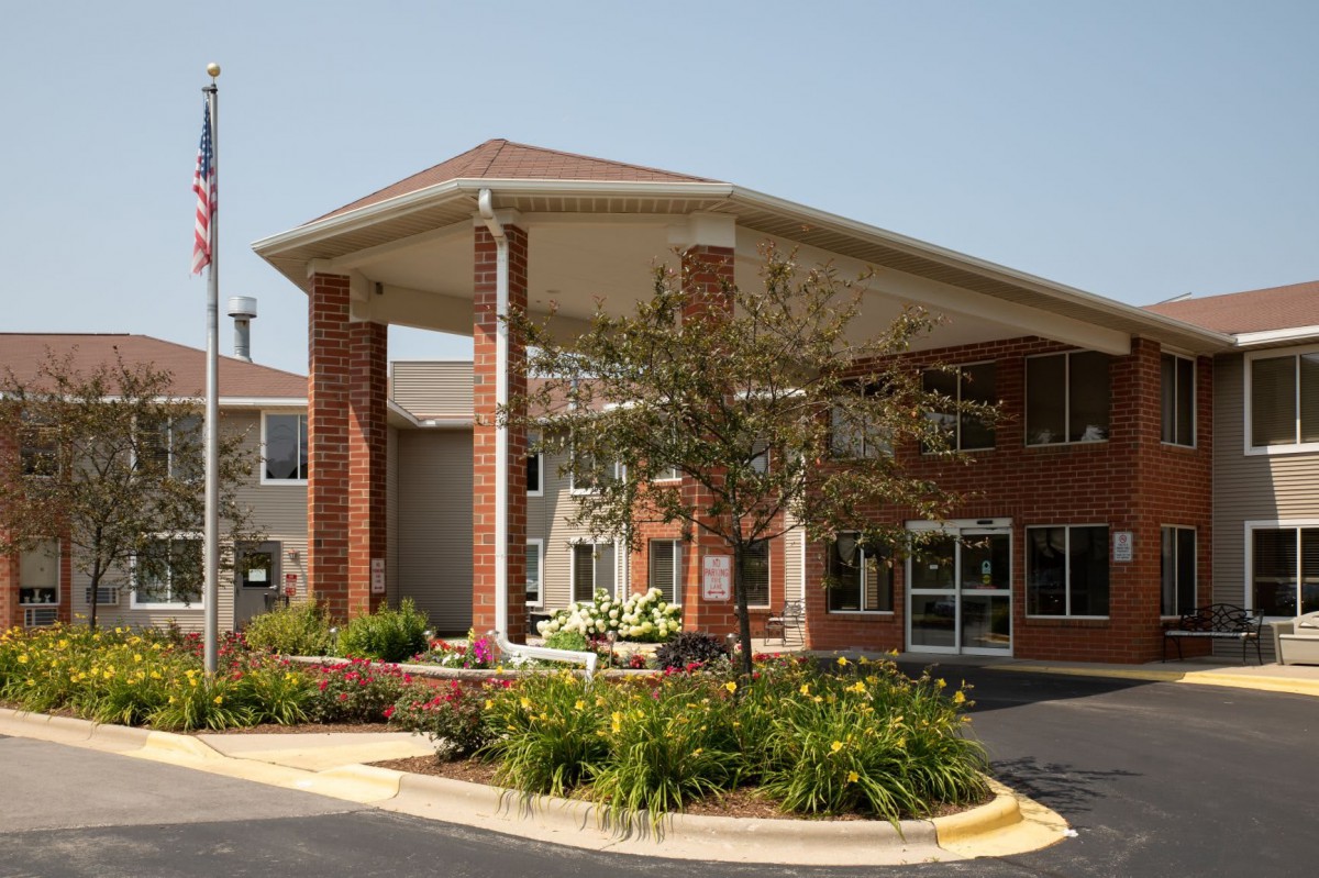 A brick building with a covered entrance and landscaped surroundings.