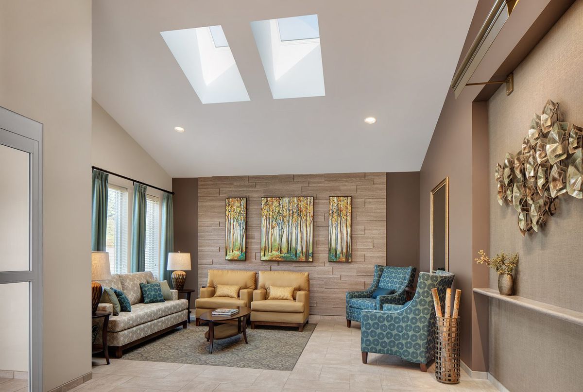A modern living room featuring skylights, comfortable seating, and tasteful wall art.