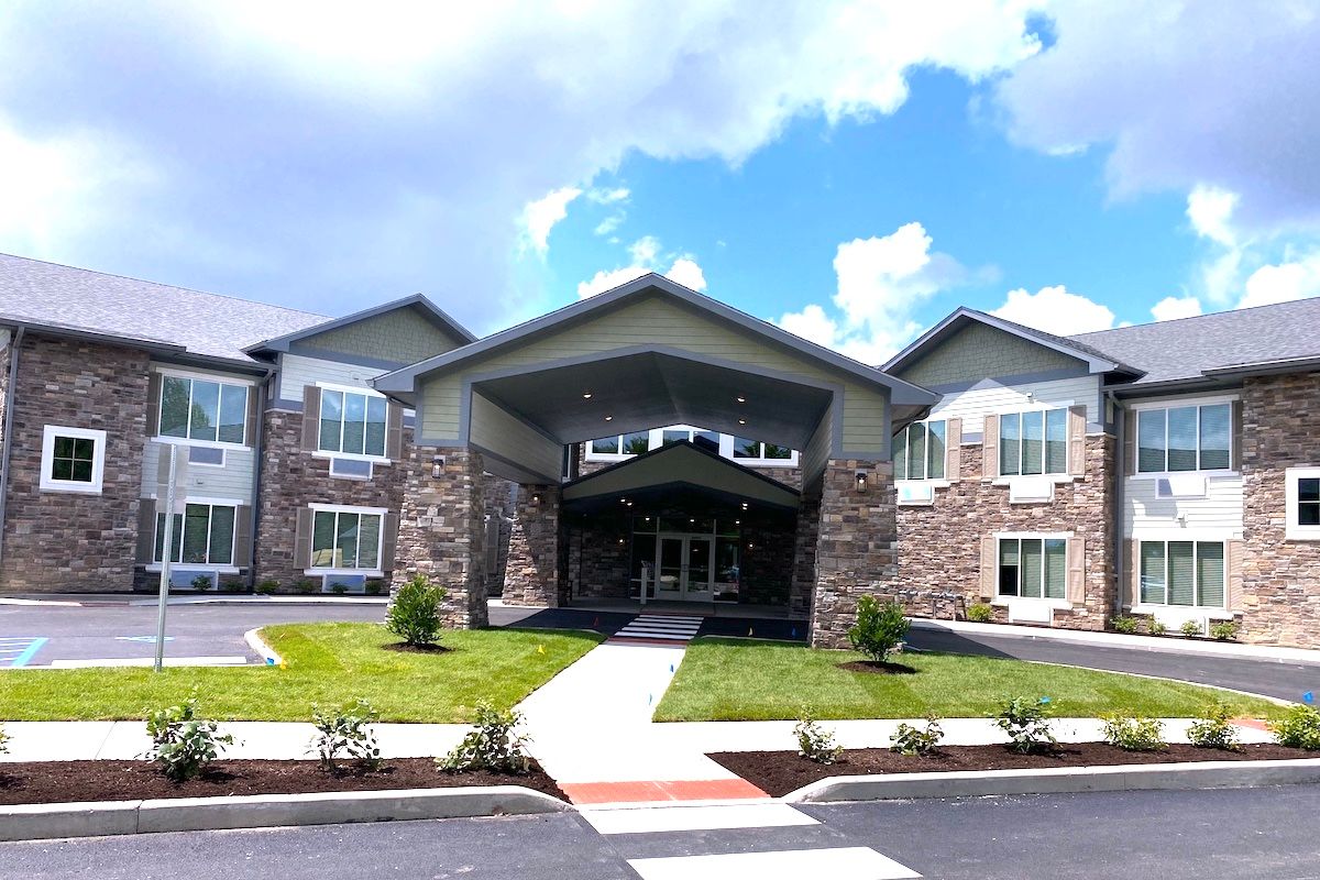 A modern building with a prominent entrance and landscaped surroundings under a partly cloudy sky.