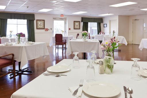 A beautifully set dining area featuring neatly arranged tables with white tablecloths and floral centerpieces, creating an inviting atmosphere.