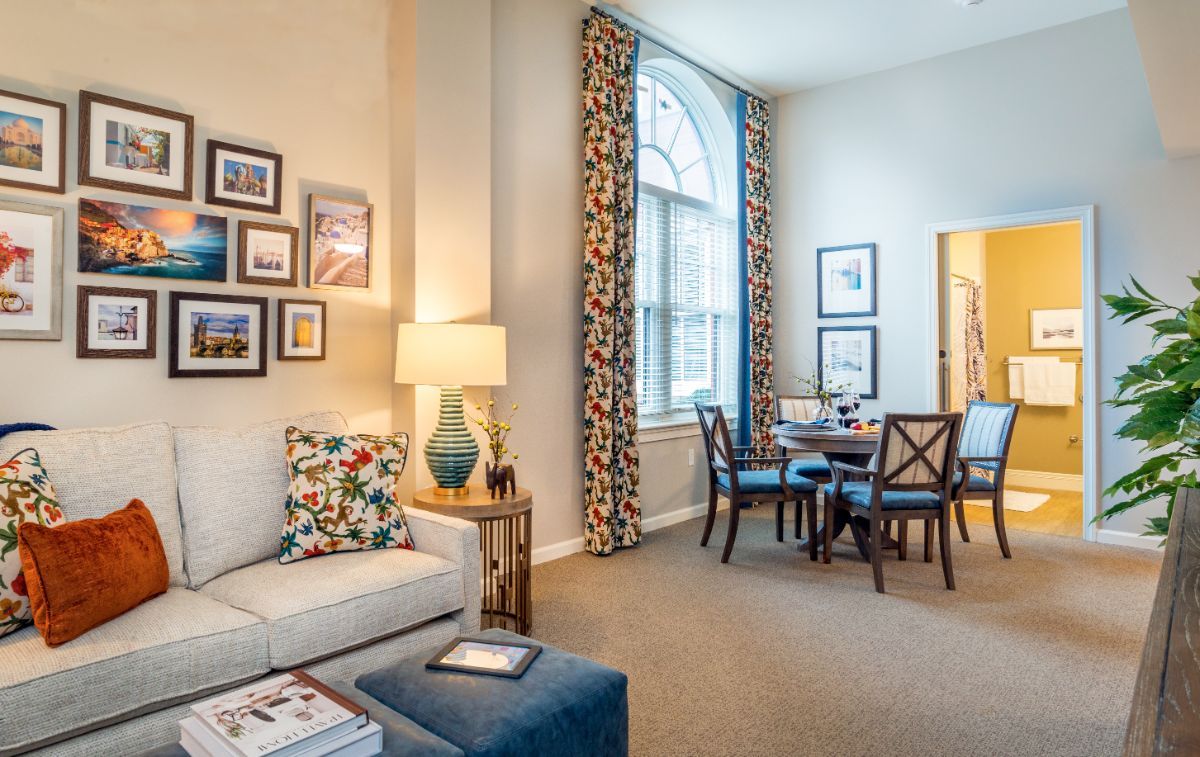 A cozy living and dining area with stylish decor, including a sofa, lamp, and wall artwork.