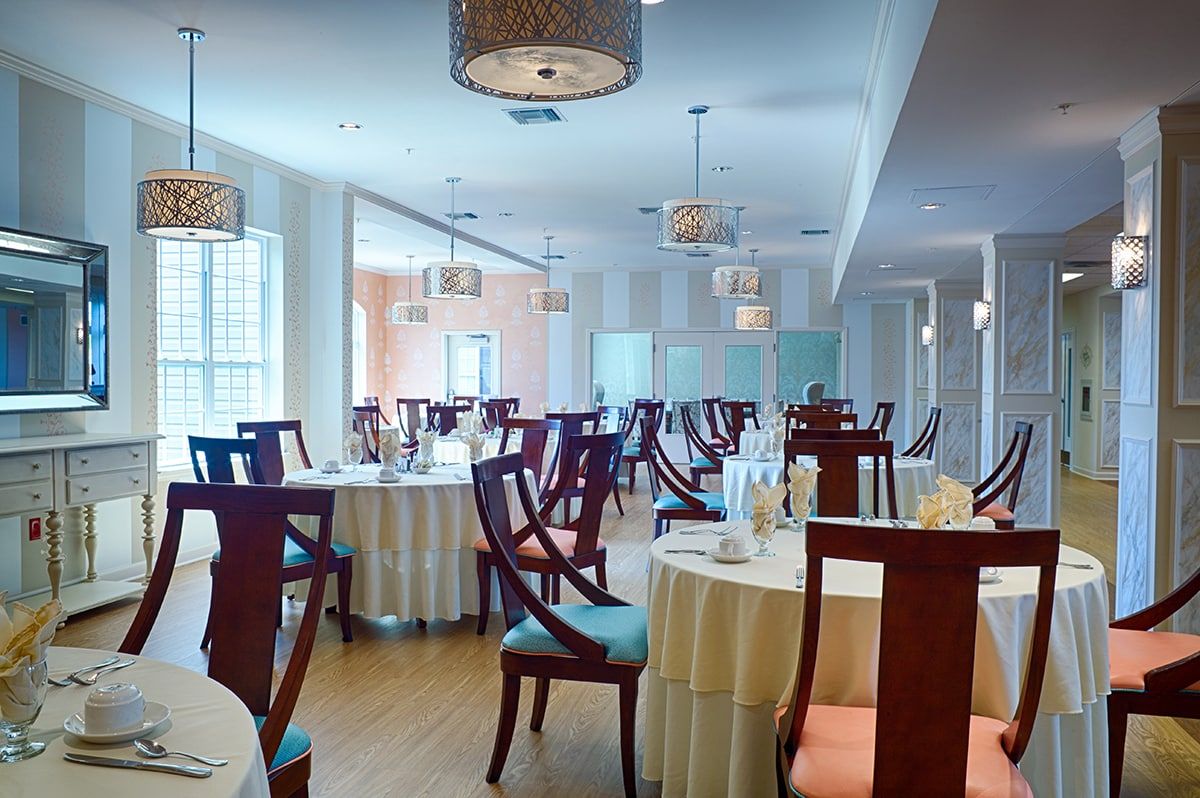 An elegant restaurant dining room with neatly arranged tables and chairs, featuring tasteful lighting fixtures.