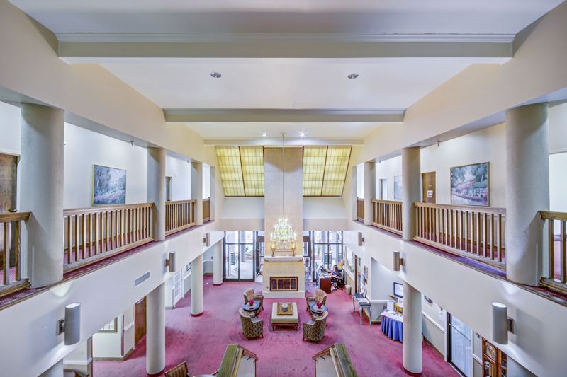 A spacious and symmetrical lobby interior featuring columns and a red carpet.