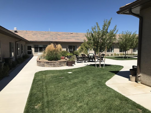 A serene outdoor space featuring a well-maintained lawn, seating area, and clear blue skies.