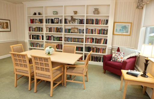 A cozy reading corner featuring a table and chairs, surrounded by shelves filled with books.
