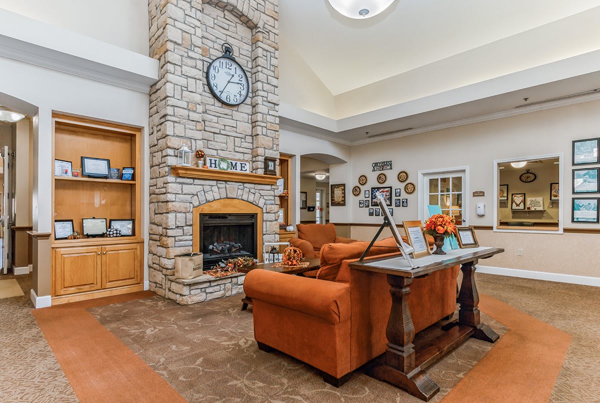 A cozy living room with a stone fireplace, central clock, and comfortable seating.