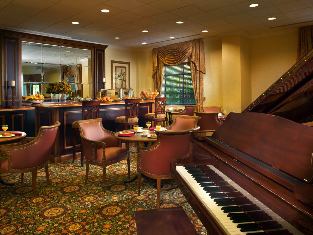 A cozy lounge featuring a piano, seating area, and bar in an elegant setting.
