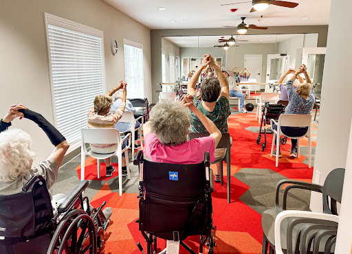 A group of elderly individuals participating in a seated exercise session at a community center.