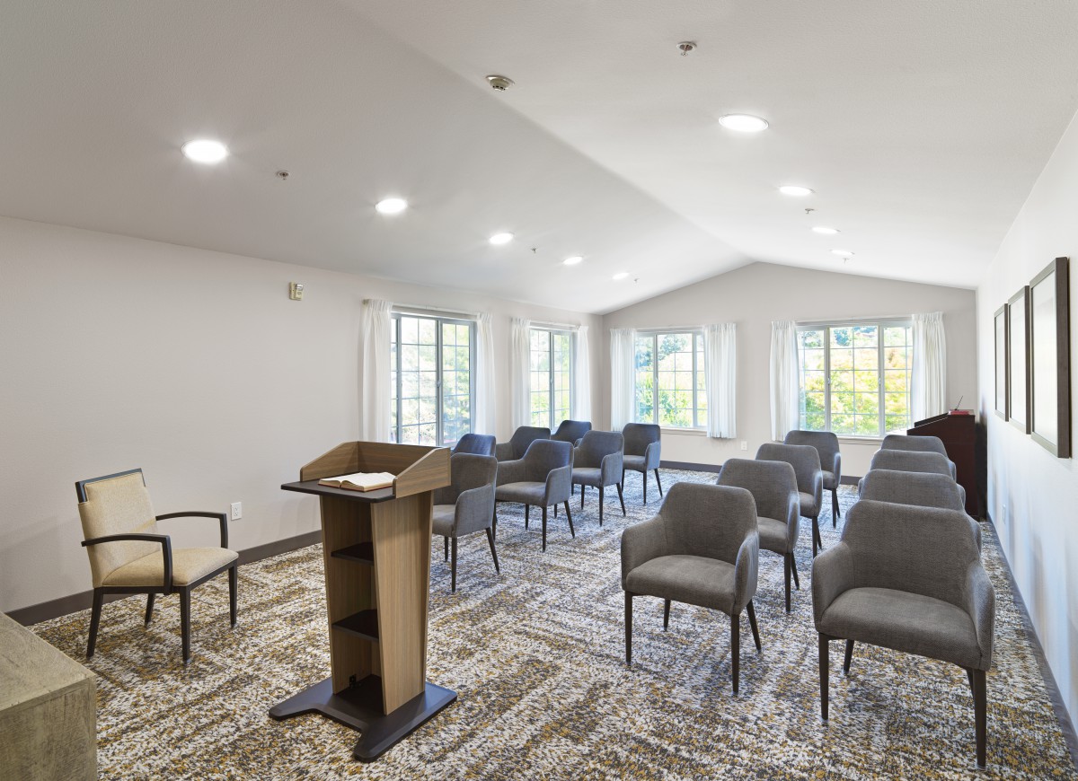A well-lit conference room with arranged chairs and a podium.