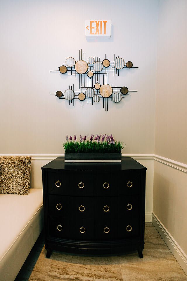 A modern interior featuring geometric wall art, a stylish black cabinet, and a decorative plant arrangement.
