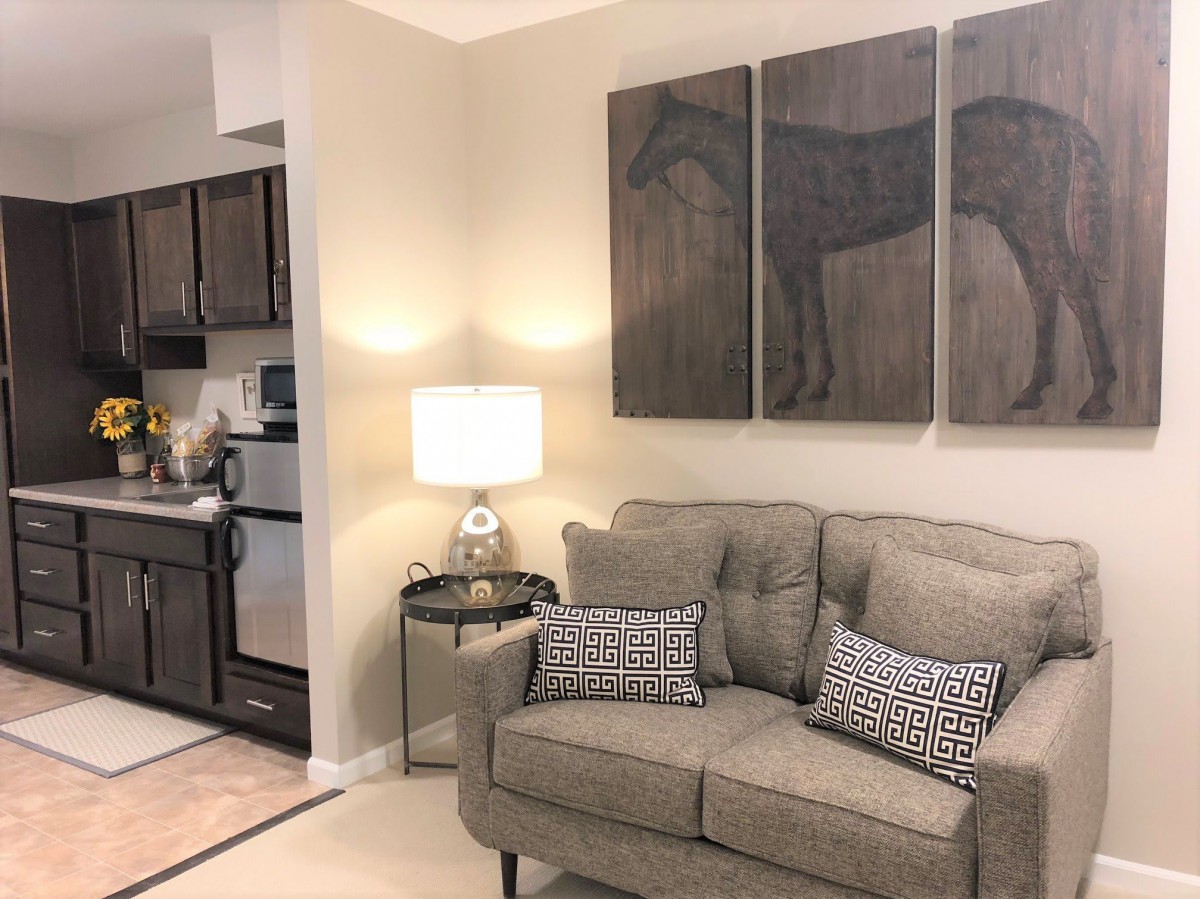 A cozy living room with a sofa, decorative artwork, and a view of the kitchen.