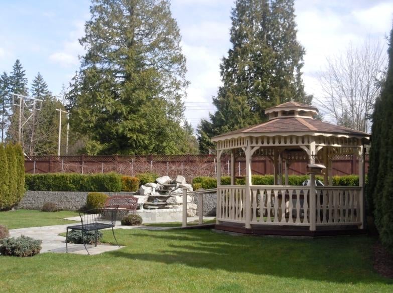 A serene garden featuring a gazebo, waterfall, and well-maintained landscaping.