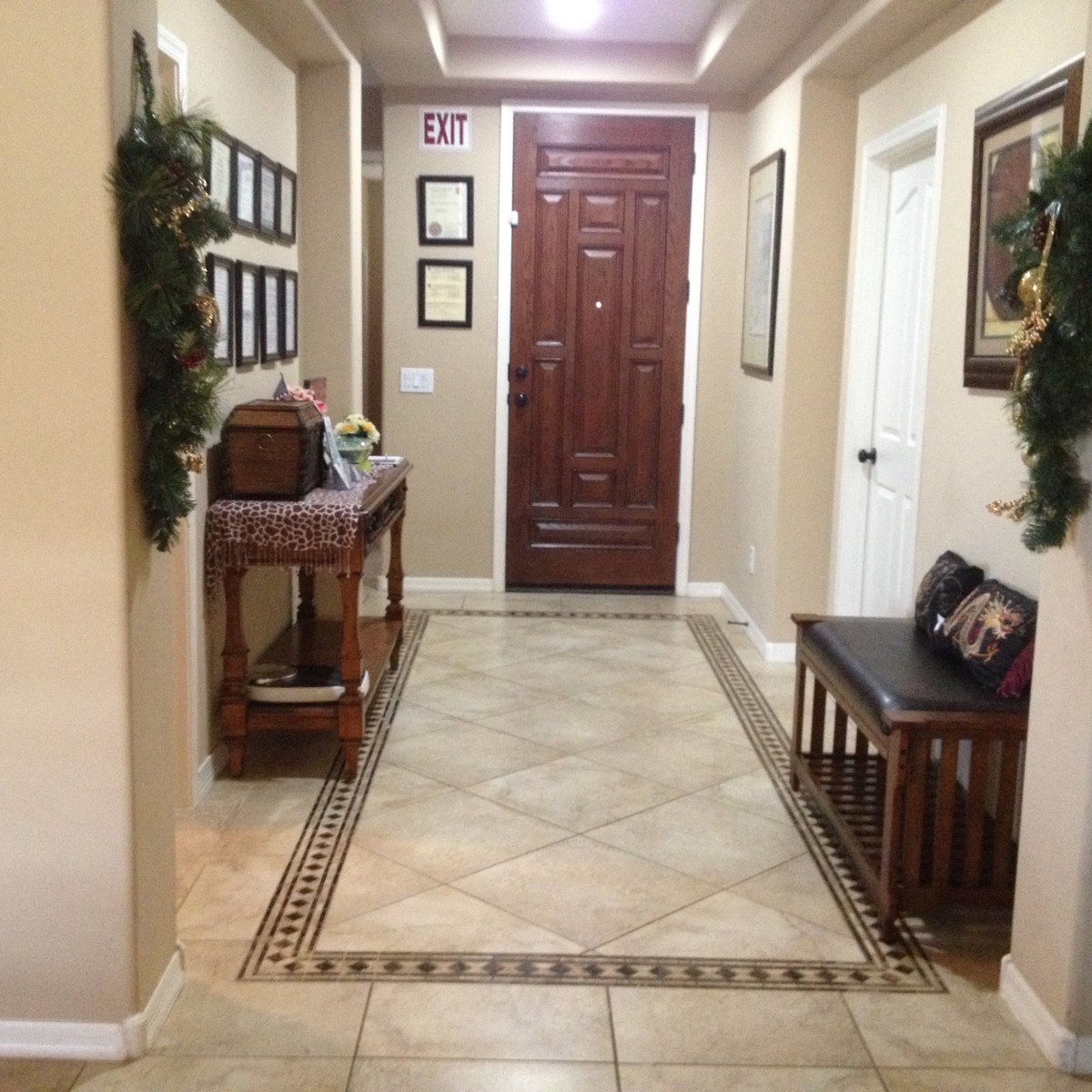 A neatly arranged hallway with decorative tiles, a wooden door, and stylish furniture.