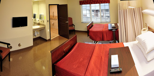 A well-furnished hotel room featuring two beds with red bedding and a cozy atmosphere.